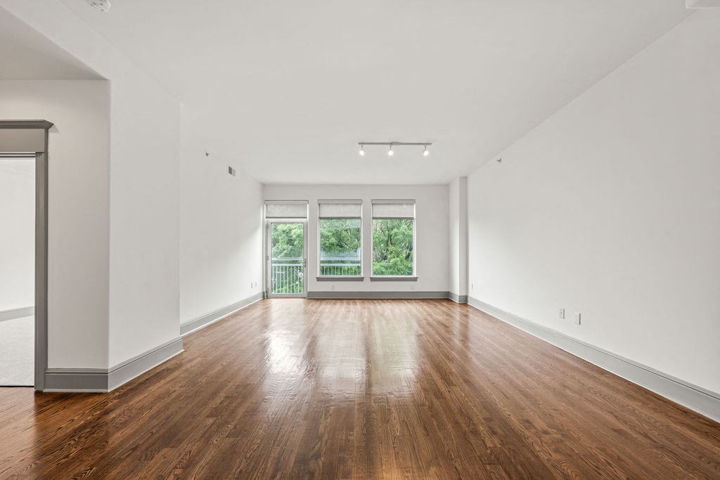 an empty living room with wood floors and a window