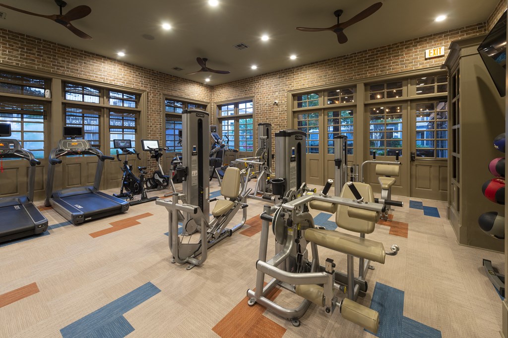 a gym with weights and cardio equipment in a building with windows