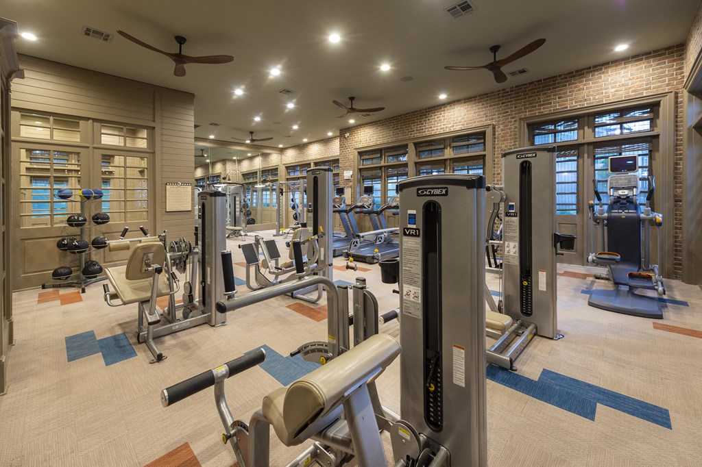 a gym with weights and cardio equipment and windows