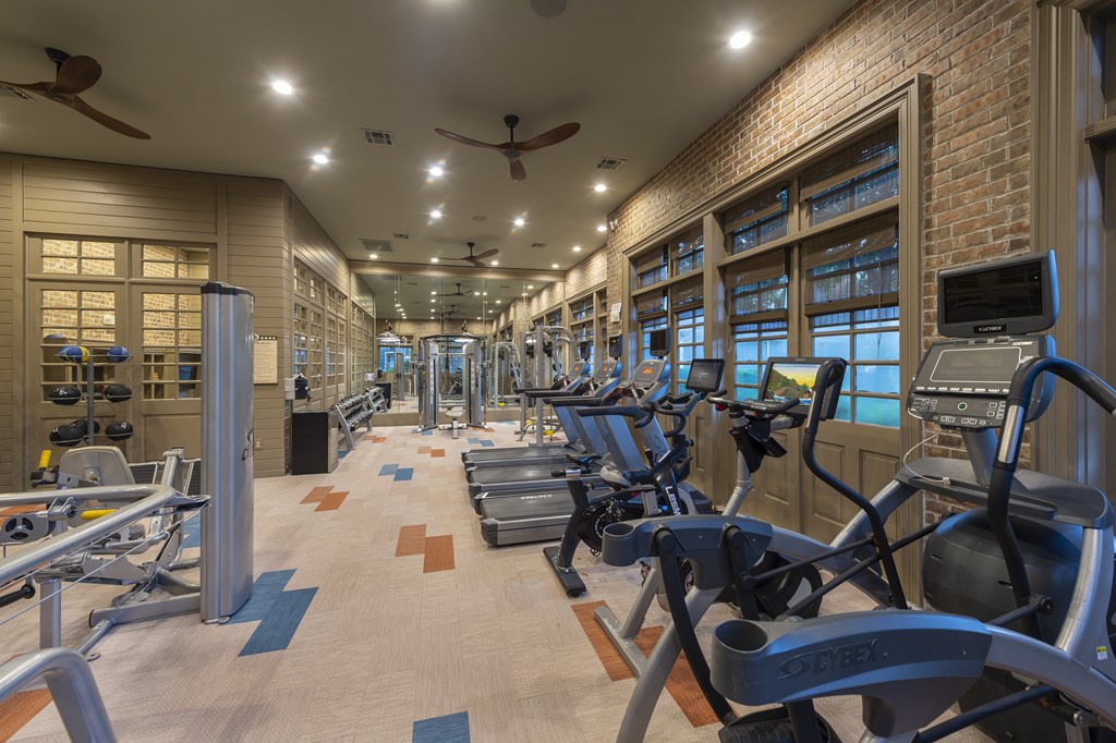 a gym with cardio equipment and a brick wall