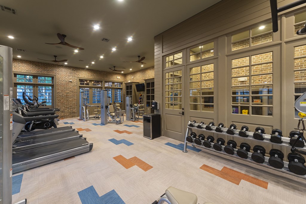 a gym with weights and a brick wall and windows