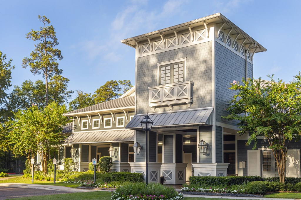 a large gray building with a porch and a tree