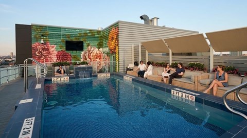 People are sitting on the sun loungers by the pool.