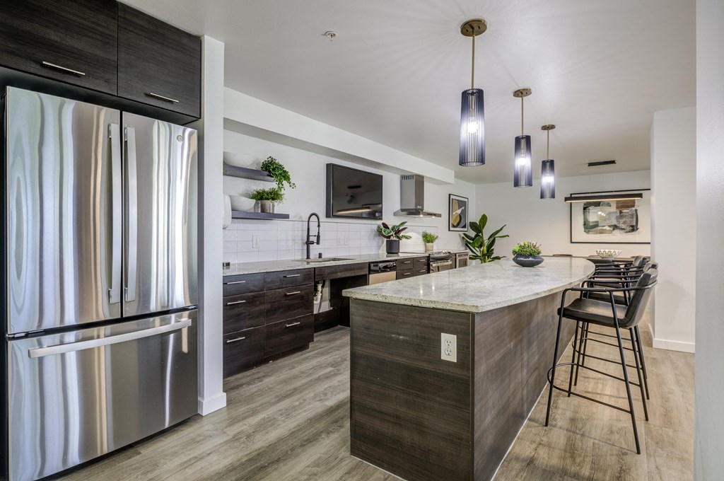 a kitchen with a large island and stainless steel refrigerator