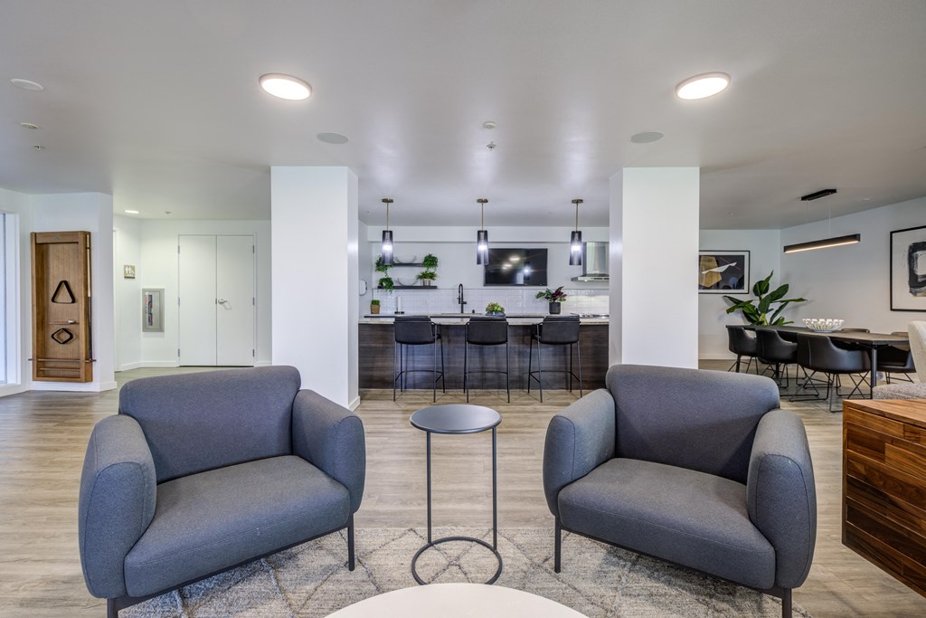 a living room with two blue chairs and a bar in the background