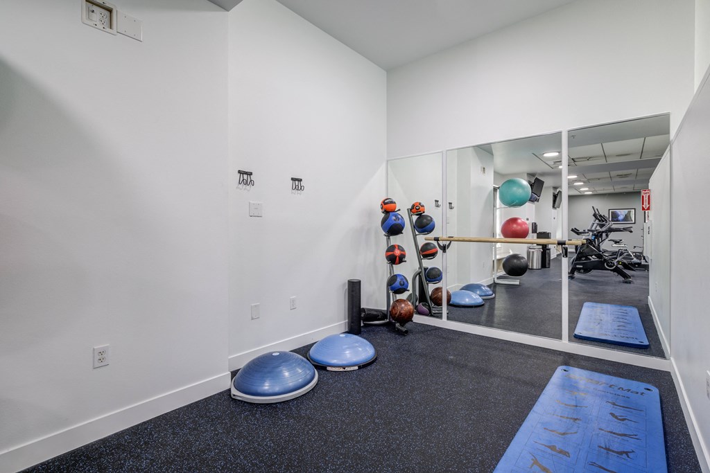 a fitness room with weights and yoga mats and a glass wall