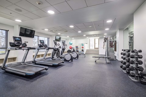 a gym with treadmills and other exercise equipment in a building with windows