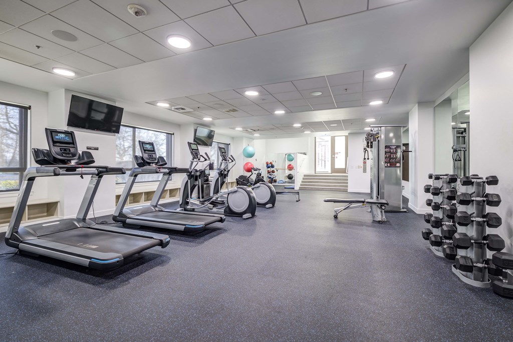 a gym with treadmills and other exercise equipment in a building with windows