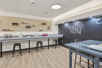 A room with a chalkboard wall and a long table with stools.