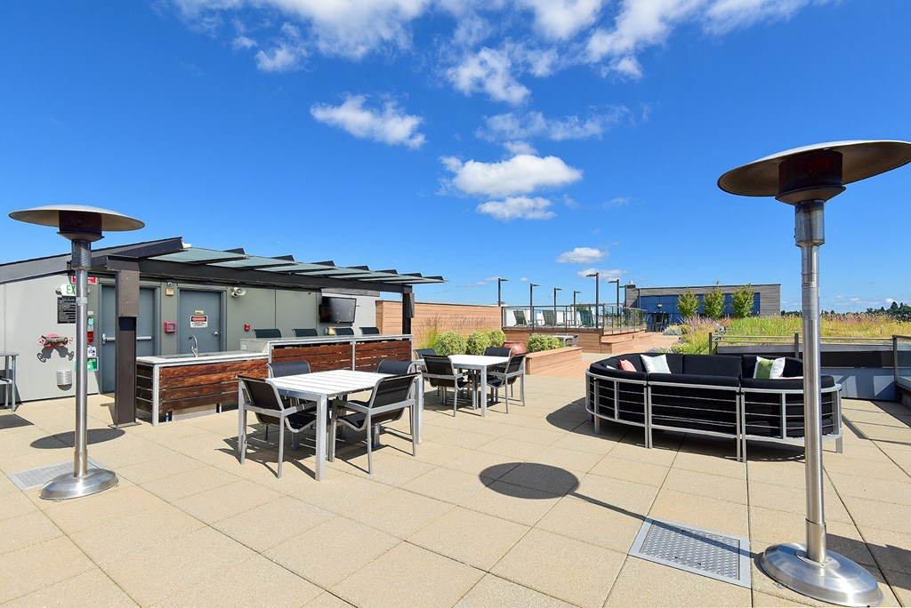 a rooftop patio with tables and chairs and a hot tub