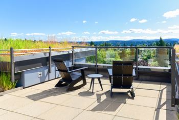 A patio with a table and chairs overlooking a green landscape.