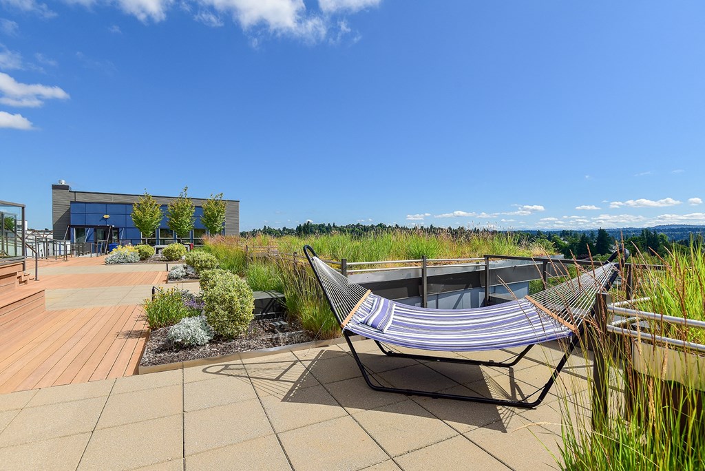 a hammock sits on a patio with plants and a building in the background