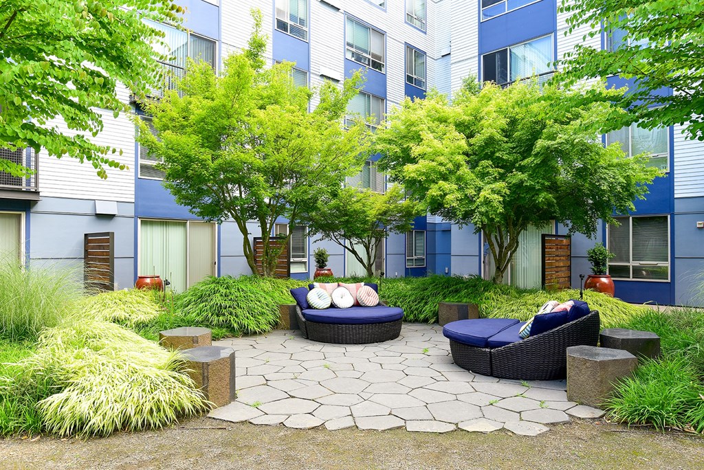a courtyard with couches and trees in front of an apartment building