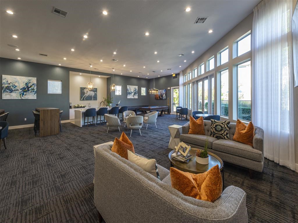 a clubhouse with couches chairs and tables and windows