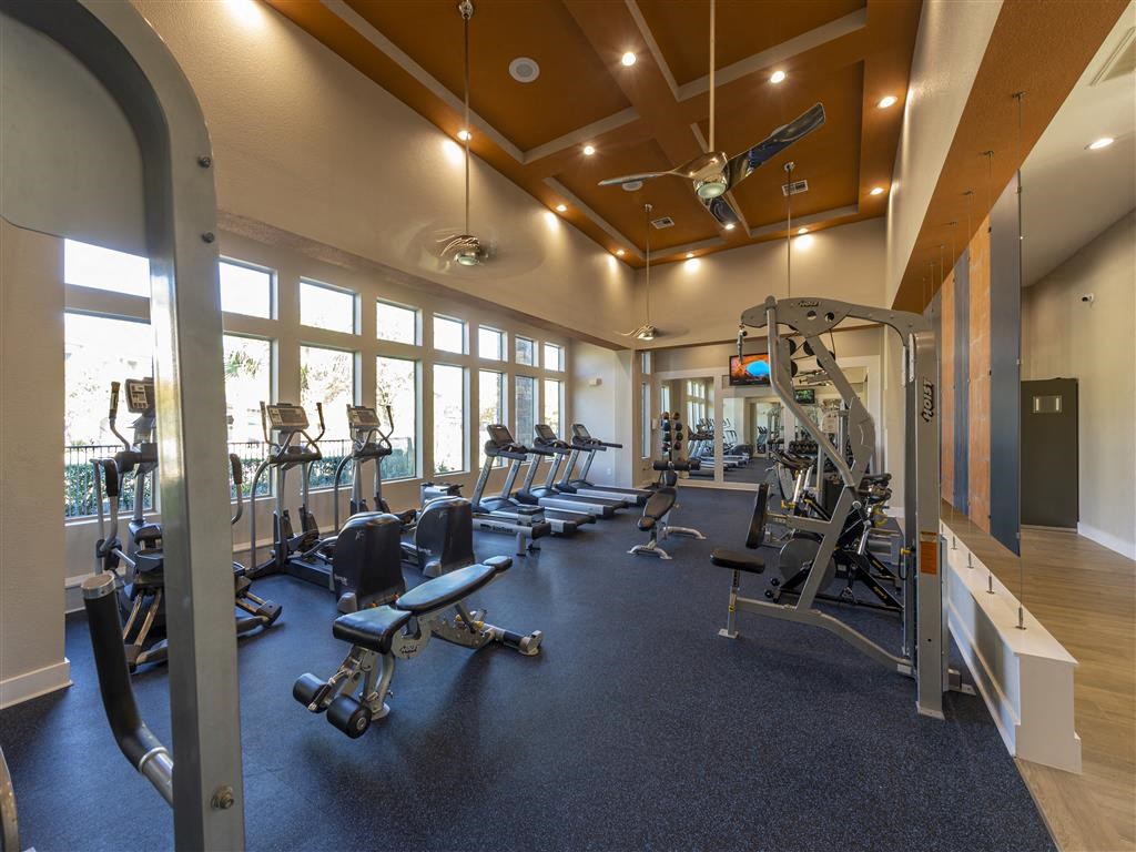 a gym with cardio equipment and windows