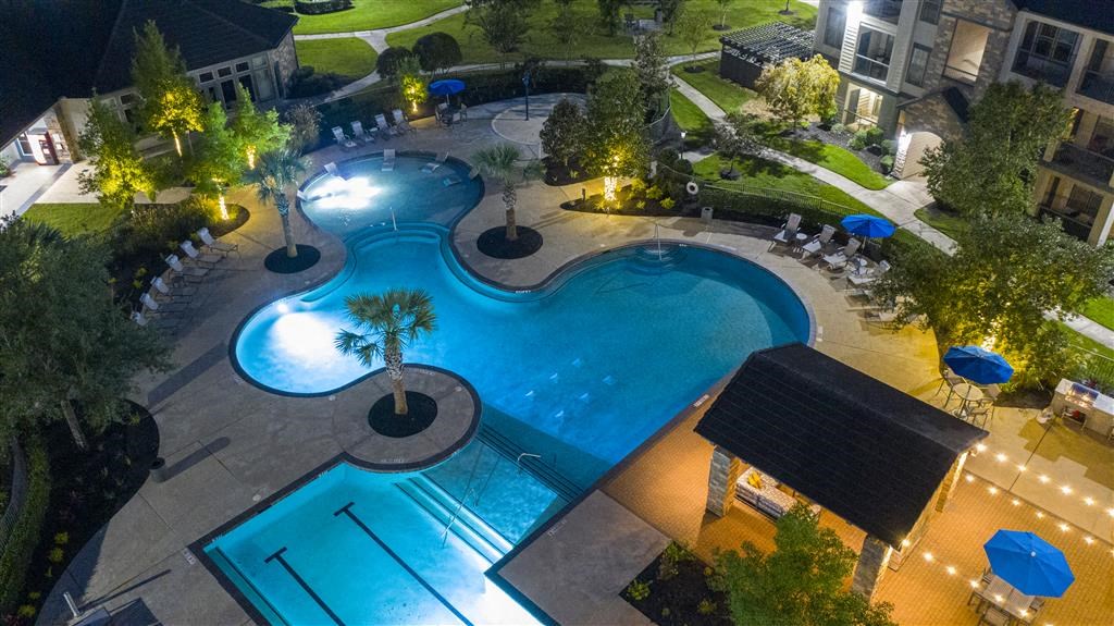 an aerial view of a swimming pool with umbrellas at night