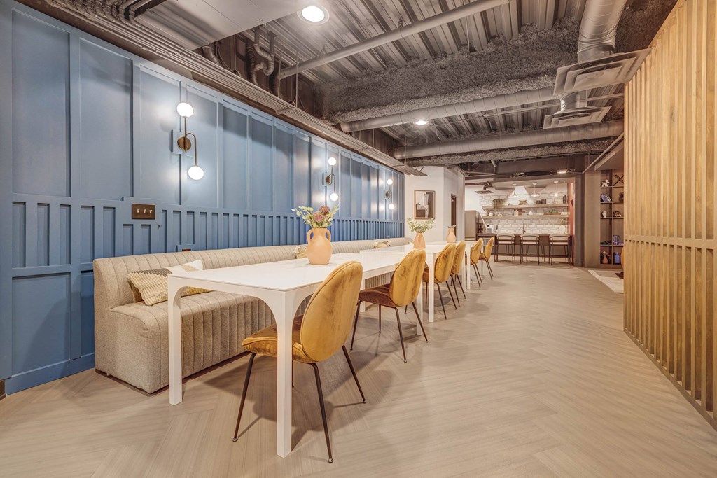 a long dining room with blue walls and a long table with yellow chairs