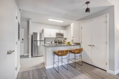 a kitchen with stainless steel appliances and a counter top with two stools