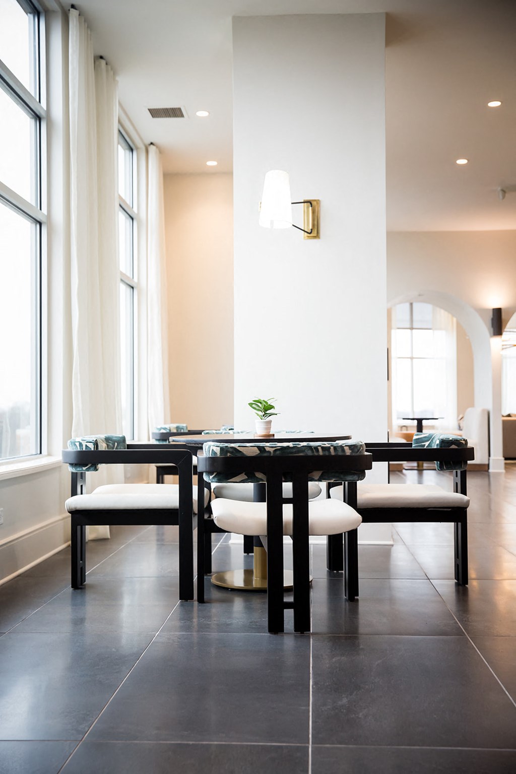 a long black table with white chairs in a room with large windows