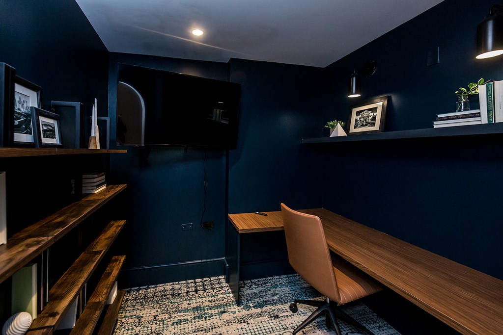 a dark blue office with a wooden desk and chair