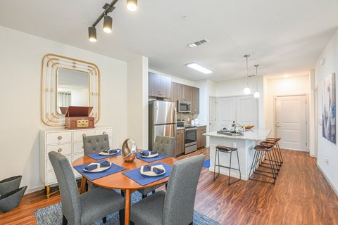 a living room with a dining room table and chairs and a kitchen with an island