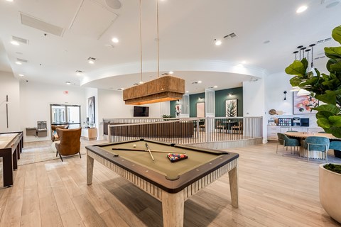 A billiard table is in the middle of a room with a pool table and a snooker table.