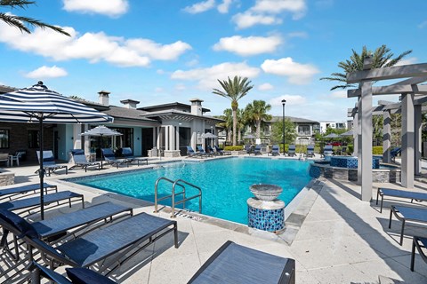 A pool surrounded by sun loungers and umbrellas.