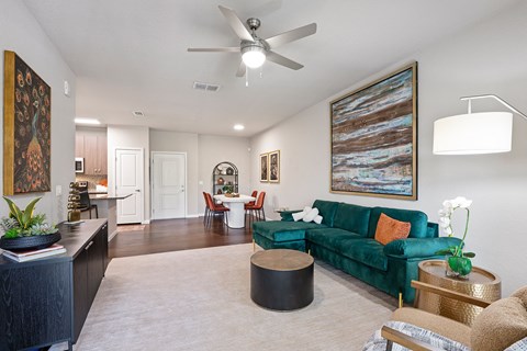 A living room with a green couch and a ceiling fan.
