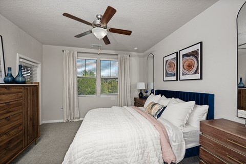 A bedroom with a bed, dresser, and ceiling fan.