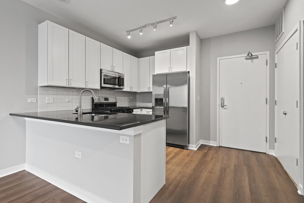 an empty kitchen with white cabinets and a black counter top