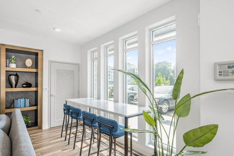 a dining room with white walls and a long white table with blue chairs