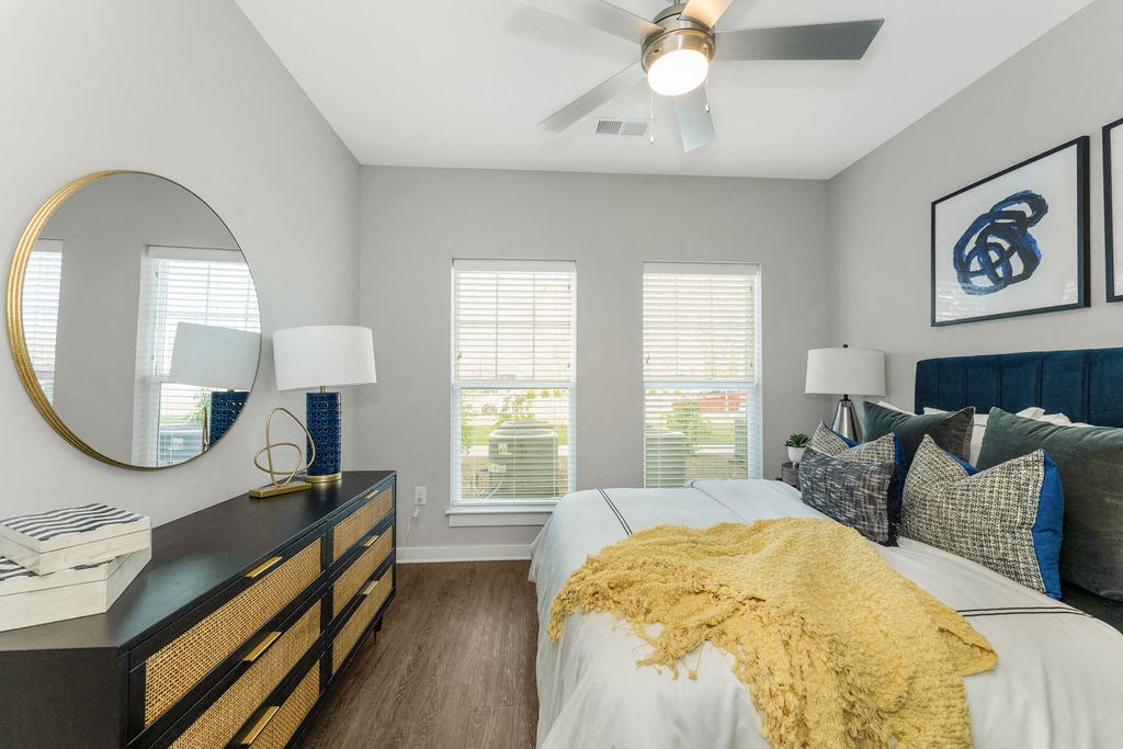 a bedroom with a ceiling fan and two windows