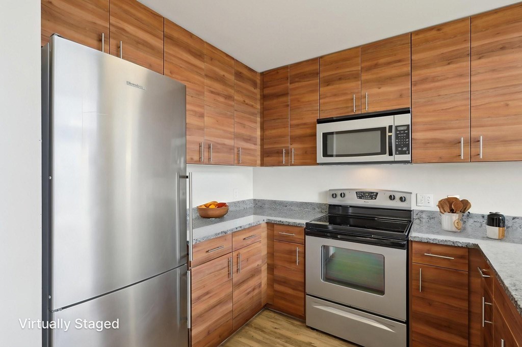 A kitchen with wooden cabinets and a stainless steel refrigerator.