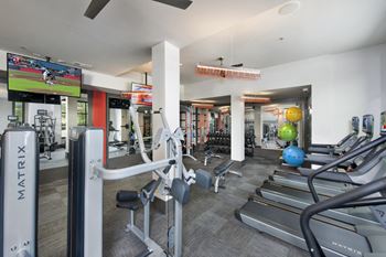 a gym with cardio equipment and a flat screen tv