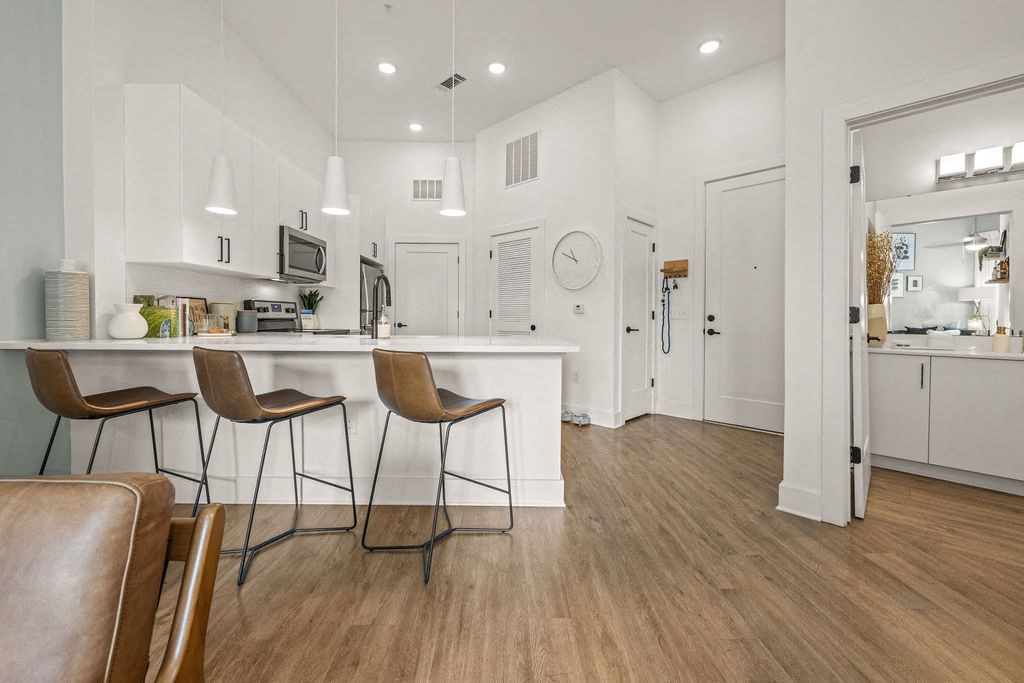 A kitchen with white cabinets and a wooden floor.