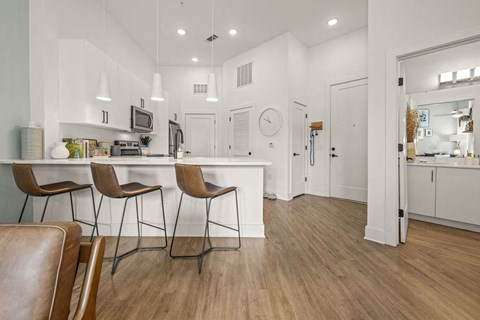 A kitchen with white cabinets and a wooden floor.