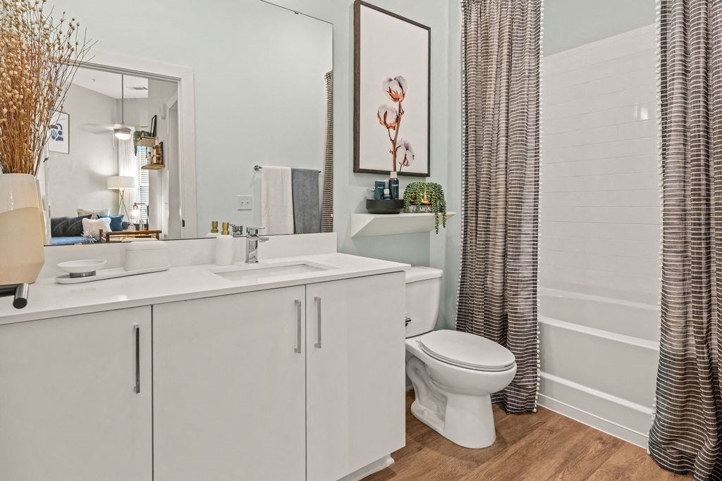 A bathroom with a white toilet, sink, and cabinets.
