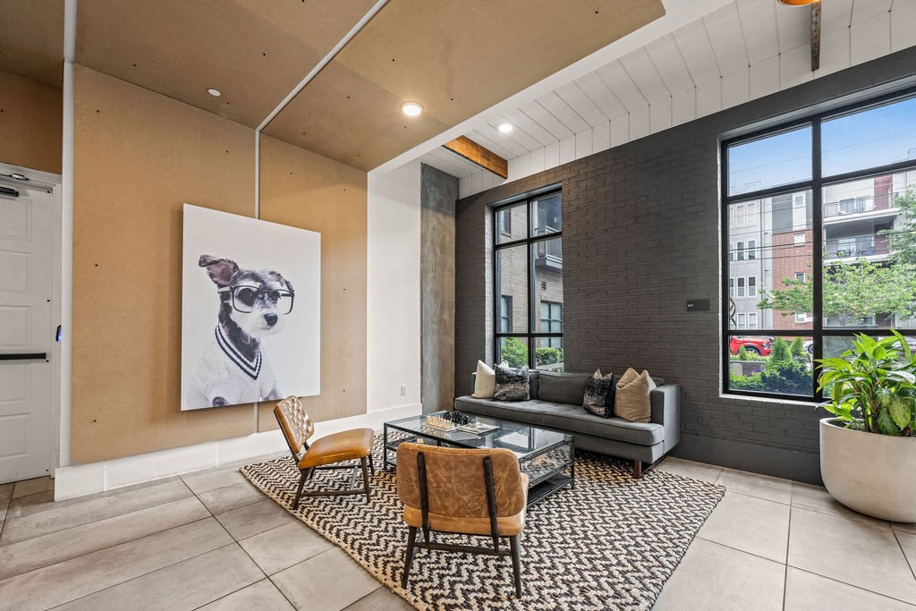 A living room with a grey sofa, a coffee table, and a painting of a dog.
