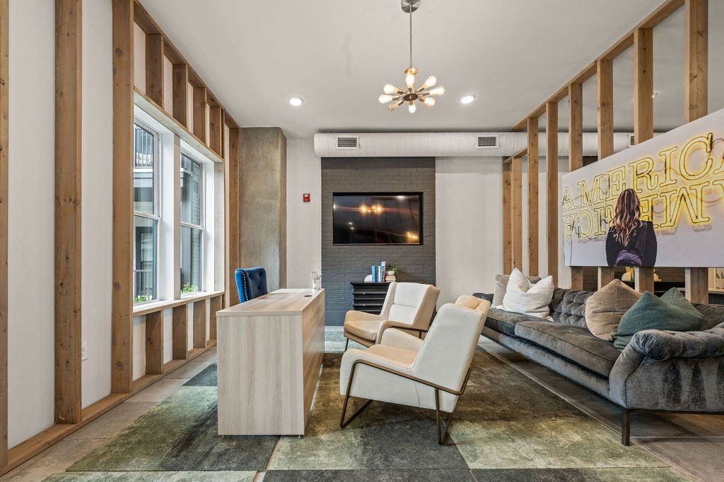A living room with a grey couch, a white chair, and a wooden cabinet.