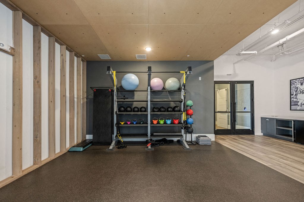 A gym with a variety of equipment including a squat rack, medicine balls, and a bench.