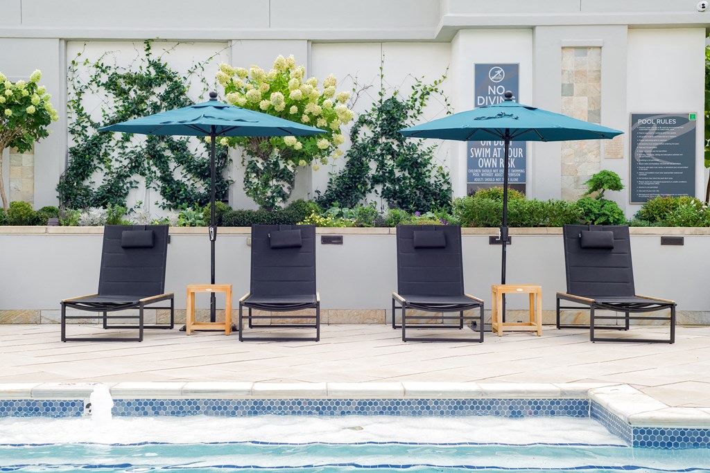 a poolside deck with lounge chairs and umbrellas