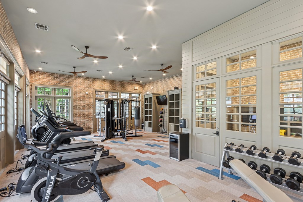 A gym with a brick wall and a row of treadmills.