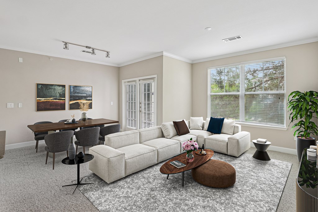 A living room with a white couch, a coffee table, and a dining table.