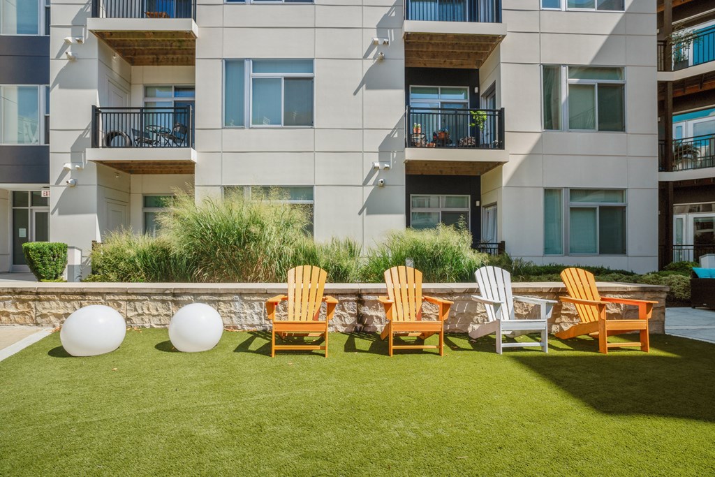 a row of adirondack chairs on a lawn in front of an apartment building at Indigo 301 Apartments, Pennsylvania, 19406