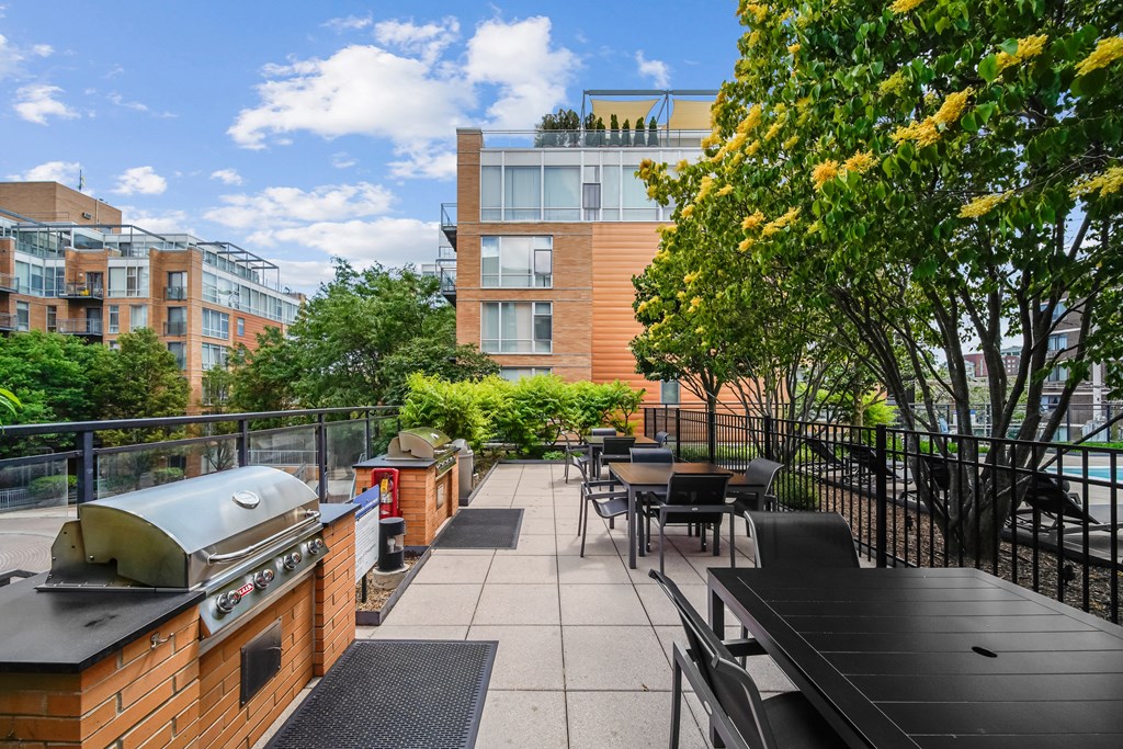 A patio with a grill and chairs overlooks a courtyard.