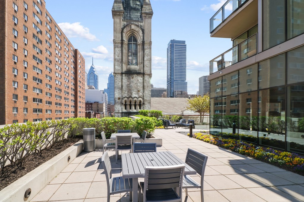 an outdoor patio with tables and chairs and a clock tower in the background