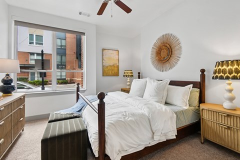 A bedroom with a large bed and a view of a city street outside the window.