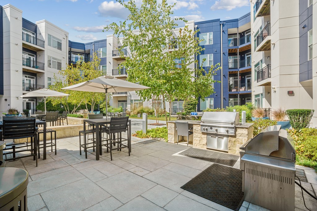 an outdoor patio with a grill and tables with umbrellas at Indigo 301 Apartments, Pennsylvania, 19406