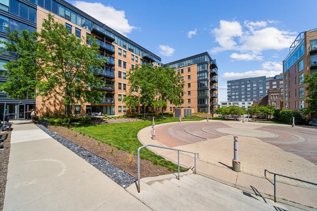 A playground with a slide and a climbing frame in the foreground with apartment buildings in the background.