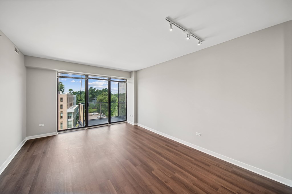 A room with wooden floors and a sliding glass door leading to a balcony.